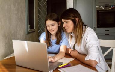 Mom helping daughter with homework on laptop